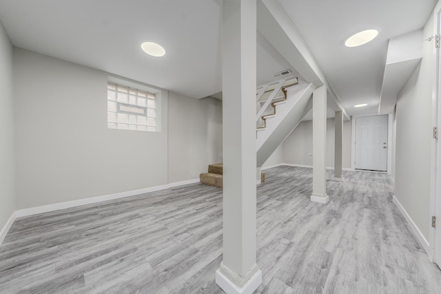 below grade area featuring baseboards, stairs, visible vents, and wood finished floors