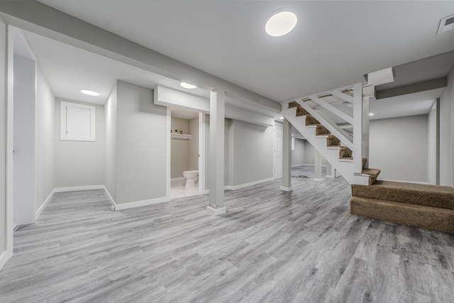 finished below grade area featuring visible vents, stairs, baseboards, and wood finished floors