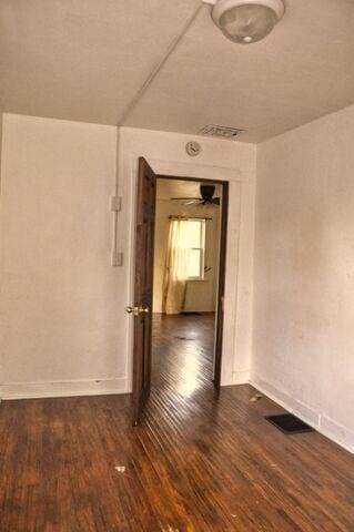spare room with visible vents, baseboards, and dark wood-style flooring