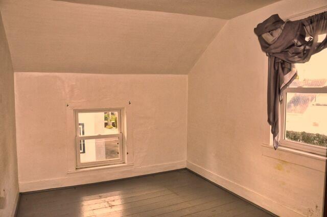 bonus room featuring vaulted ceiling, baseboards, and dark wood-style flooring