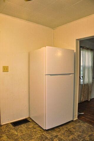 kitchen with freestanding refrigerator, visible vents, and stone finish flooring