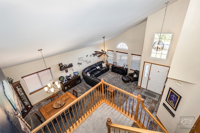 stairway featuring ceiling fan with notable chandelier and high vaulted ceiling