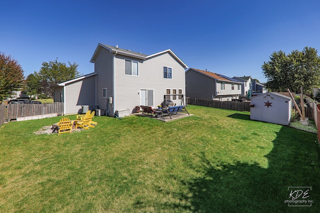 back of property featuring a shed, a lawn, an outdoor fire pit, and central AC unit