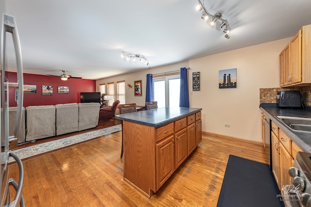 kitchen featuring ceiling fan, a kitchen island, rail lighting, stainless steel appliances, and light wood-type flooring