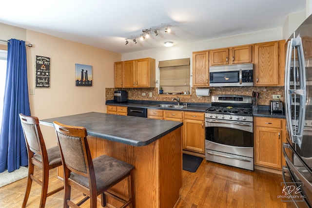 kitchen with a kitchen breakfast bar, decorative backsplash, dark hardwood / wood-style flooring, stainless steel appliances, and sink