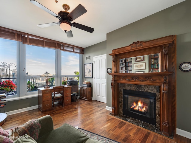 living room with hardwood / wood-style floors, ceiling fan, and a premium fireplace