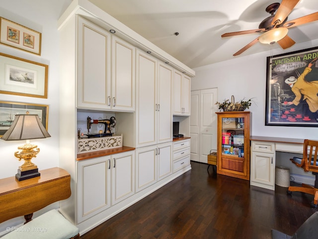 kitchen featuring ceiling fan, white cabinets, built in desk, and dark hardwood / wood-style flooring