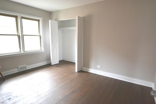 unfurnished bedroom featuring dark wood-type flooring and a closet