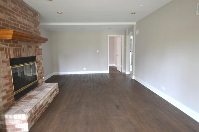 unfurnished living room featuring a brick fireplace and dark hardwood / wood-style flooring