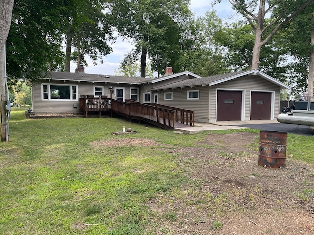 back of property with an outbuilding, a garage, a lawn, and a wooden deck