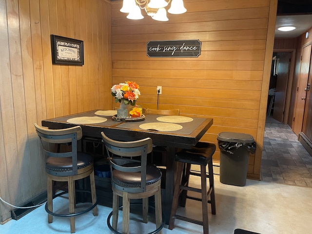 dining space with wood walls and an inviting chandelier