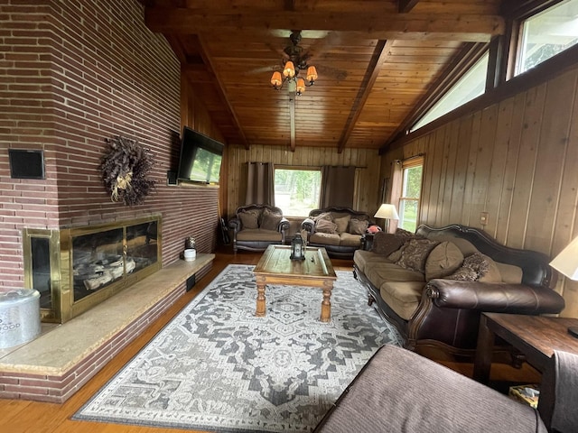 living room featuring hardwood / wood-style floors, ceiling fan, a fireplace, beam ceiling, and wood ceiling