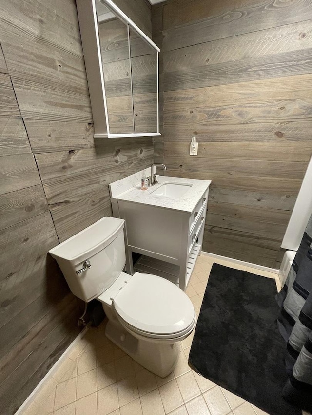 bathroom featuring wooden walls, tile patterned flooring, vanity, and toilet