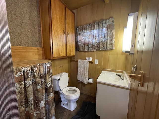 bathroom featuring vanity, toilet, and wood walls