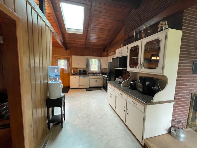 kitchen featuring dishwasher, lofted ceiling with skylight, wooden ceiling, white cabinets, and wooden walls