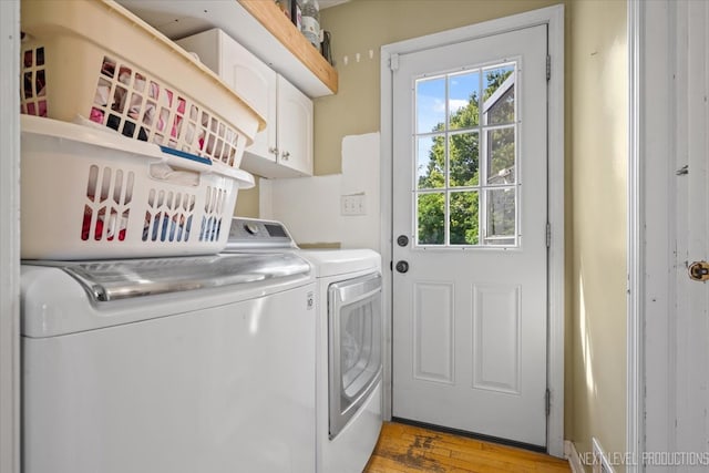 laundry room featuring light wood-type flooring, cabinets, and washer and clothes dryer