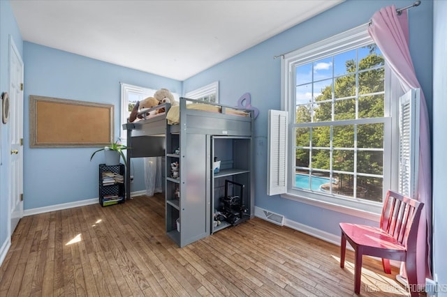 bedroom with multiple windows and hardwood / wood-style floors