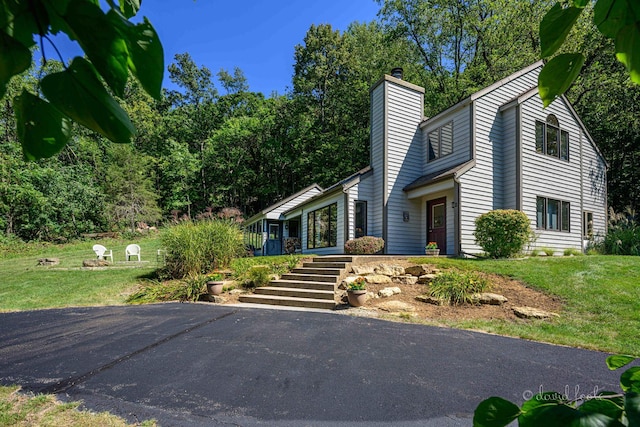 view of side of home featuring stairway, a lawn, and a chimney