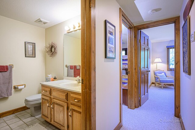 bathroom featuring vanity, toilet, tile patterned floors, and a textured ceiling