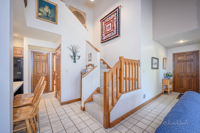 foyer entrance with a towering ceiling and light tile patterned floors