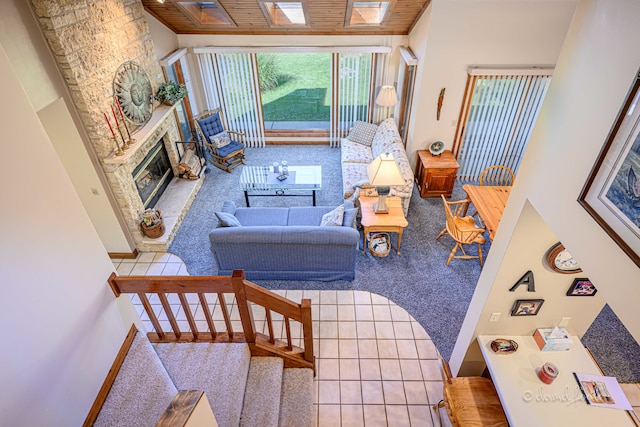 carpeted living room featuring wood ceiling, a high ceiling, a skylight, and a fireplace