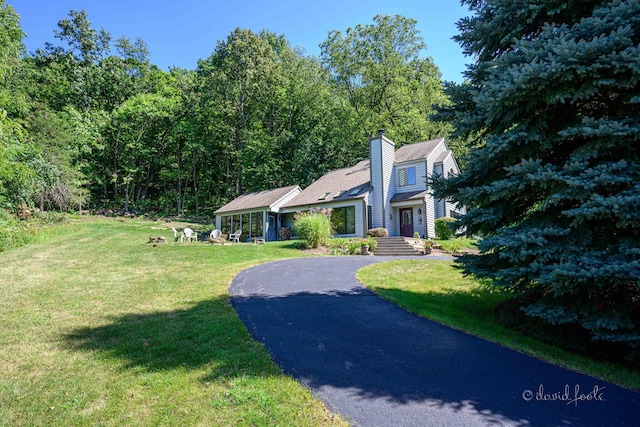 view of front of property with a front lawn, driveway, and a chimney