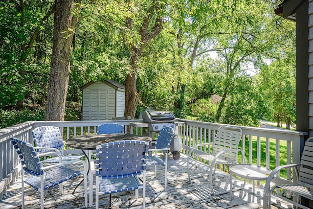 deck featuring a storage unit, an outbuilding, outdoor dining area, and grilling area