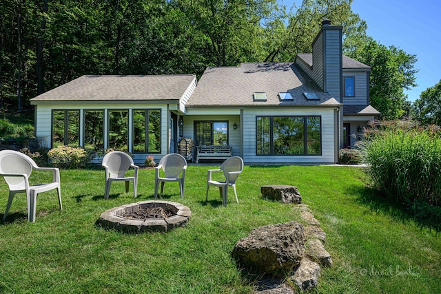 rear view of house with a lawn and an outdoor fire pit