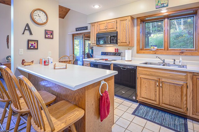 kitchen featuring black appliances, a breakfast bar area, light tile patterned floors, and sink