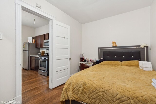 bedroom with dark hardwood / wood-style floors and stainless steel fridge