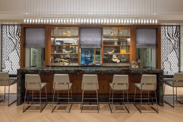 bar featuring pendant lighting, dark stone counters, and light parquet flooring