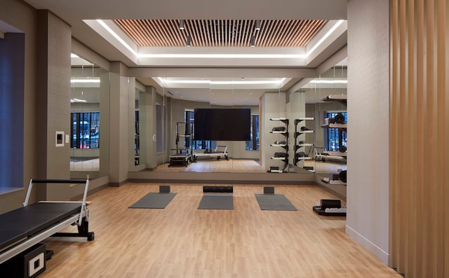 workout area featuring light hardwood / wood-style flooring and a raised ceiling