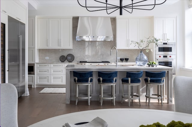 kitchen featuring sink, wall chimney range hood, white cabinetry, appliances with stainless steel finishes, and dark hardwood / wood-style flooring