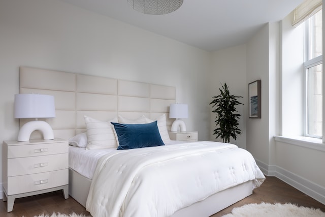 bedroom with multiple windows and dark hardwood / wood-style floors