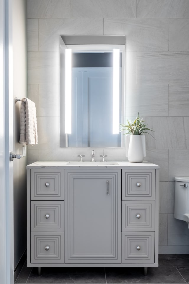 bathroom featuring tile patterned floors, toilet, vanity, and tile walls