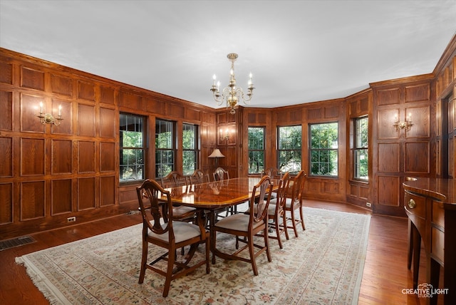 dining room with wooden walls, dark hardwood / wood-style floors, a chandelier, and crown molding