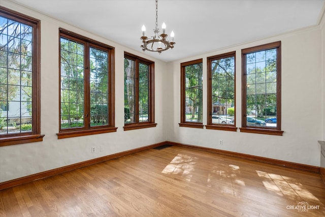 spare room with light hardwood / wood-style flooring, a notable chandelier, and crown molding