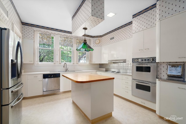 kitchen featuring appliances with stainless steel finishes, decorative backsplash, white cabinets, pendant lighting, and a center island