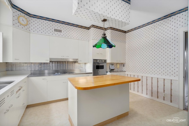 kitchen with a center island, white cabinets, butcher block counters, oven, and decorative light fixtures