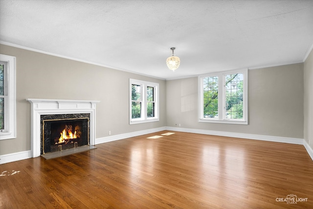 unfurnished living room featuring a high end fireplace, a textured ceiling, hardwood / wood-style flooring, and crown molding