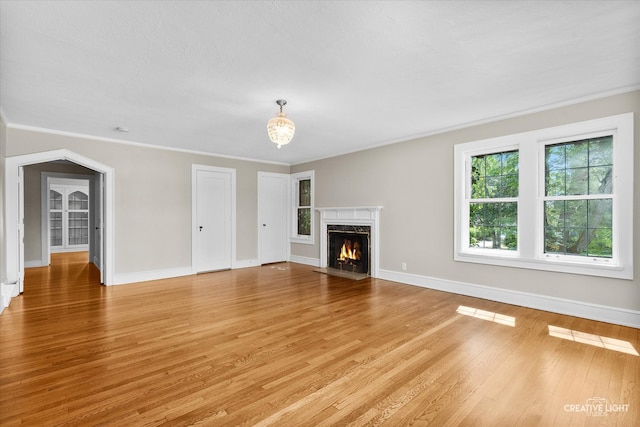 unfurnished living room featuring light wood-type flooring, crown molding, and a high end fireplace