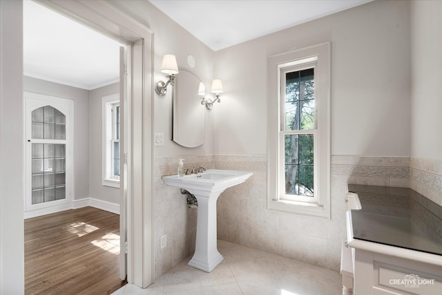 bathroom with crown molding, wood-type flooring, and tile walls