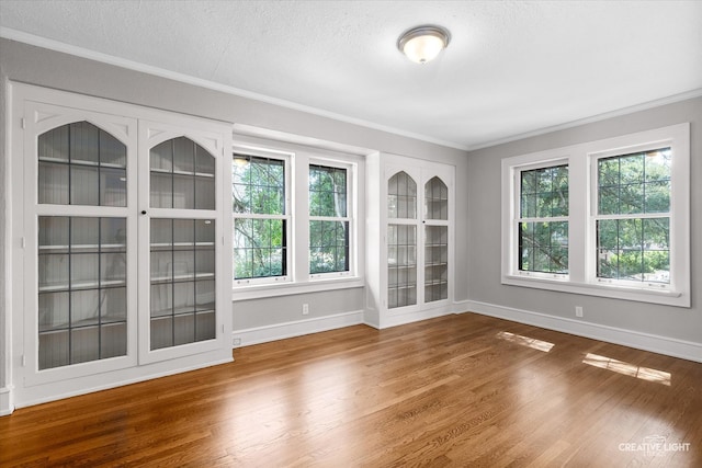 spare room with a wealth of natural light, wood-type flooring, and crown molding