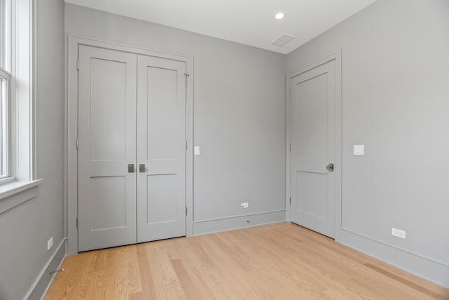 unfurnished bedroom with light hardwood / wood-style flooring and a closet