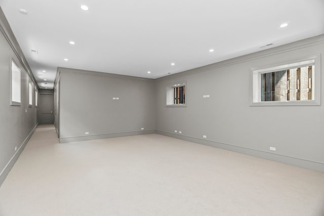 basement with light colored carpet and crown molding