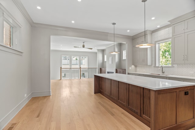 kitchen with backsplash, light wood-type flooring, decorative light fixtures, sink, and ceiling fan