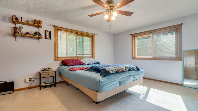 bedroom with ceiling fan, light carpet, and a textured ceiling