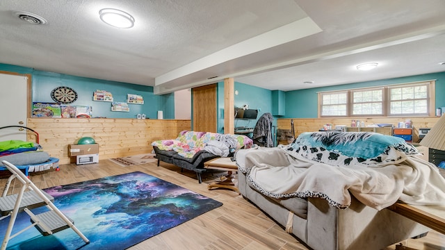 bedroom featuring a textured ceiling, hardwood / wood-style flooring, and wood walls