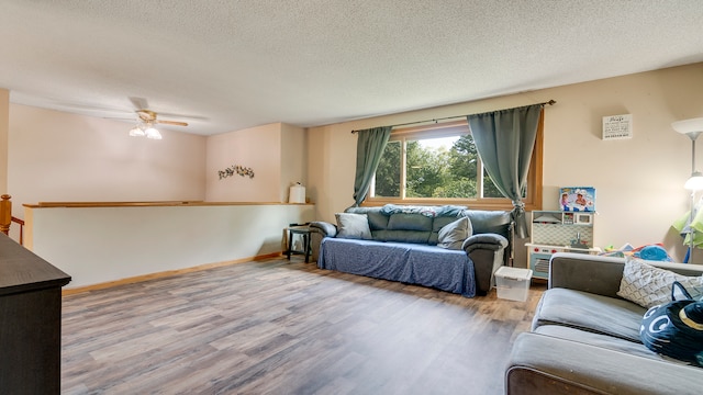 living room with a textured ceiling, ceiling fan, and wood-type flooring