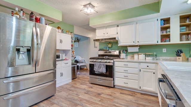 kitchen with a textured ceiling, light hardwood / wood-style flooring, stainless steel appliances, sink, and white cabinetry